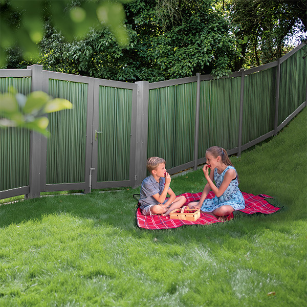 Sichtschutzzaun mit grünem Rasen und spielenden Kindern